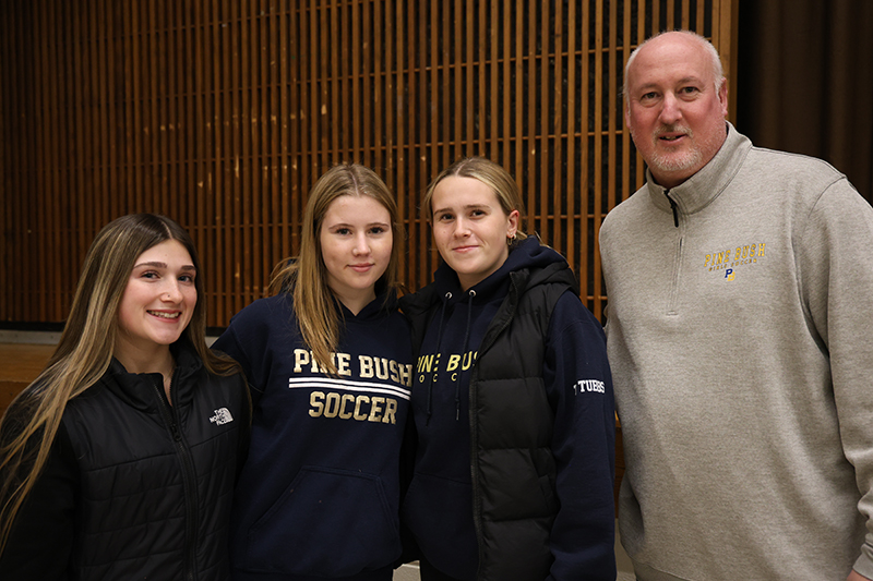 A man stands on the right with three young women.