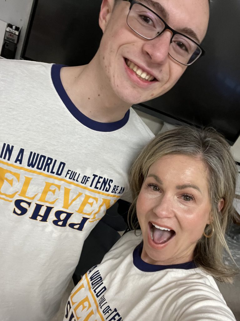 A woman and young man smile as they take a selfie.