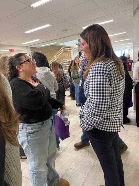 A young woman talks to a woman in a group of people.