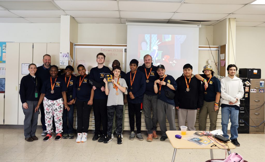 A group of 13 people stand together smiling, 10 high school students and three adults.