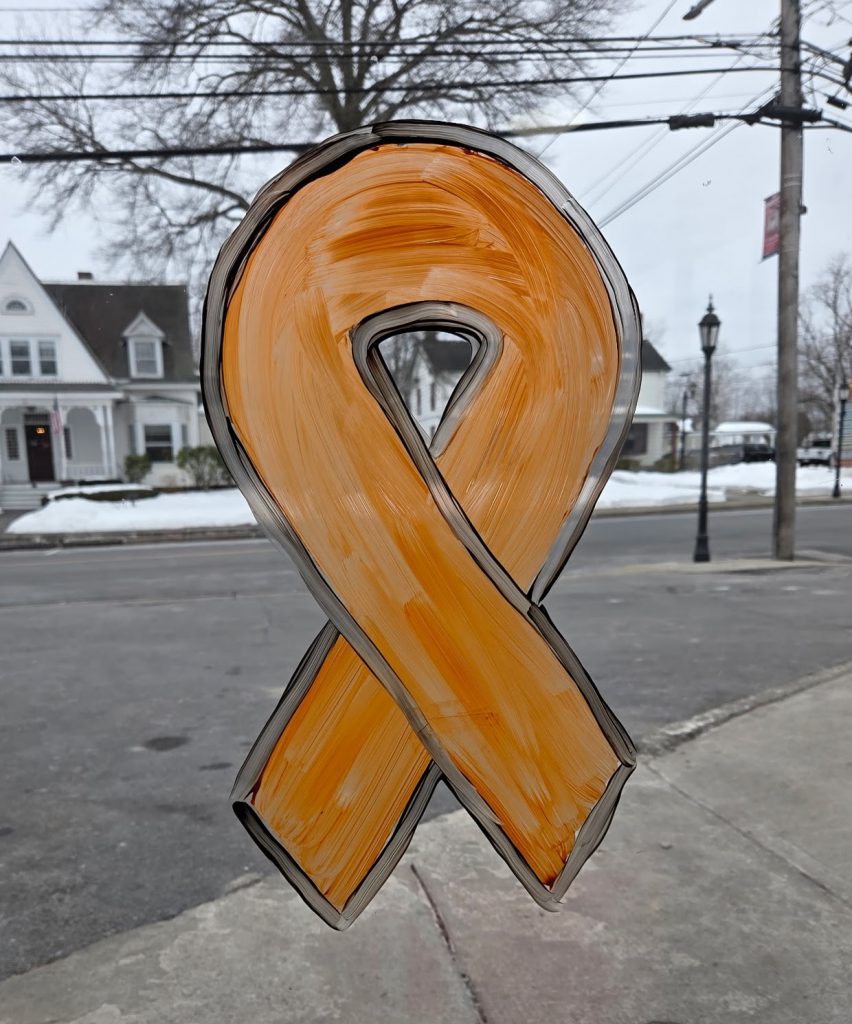 looking through a plate glass storefront. There is an orange ribbon painted on it, outlined in black.