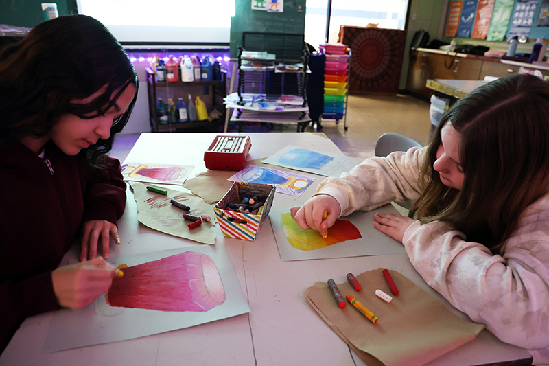 Two middle school girls draw and color large ring pops.