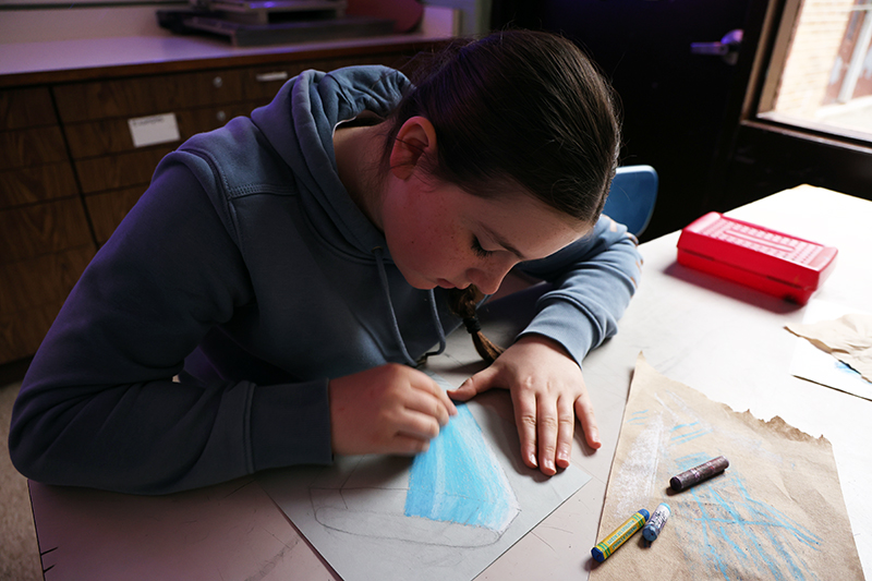 A middle school student draws a blue ring pop.