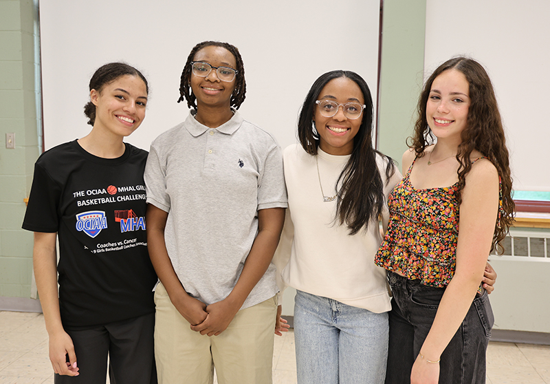 Four young women smile and stand together.