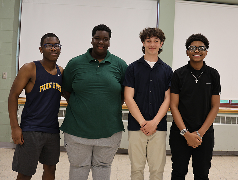 Four young men smile and stand together.