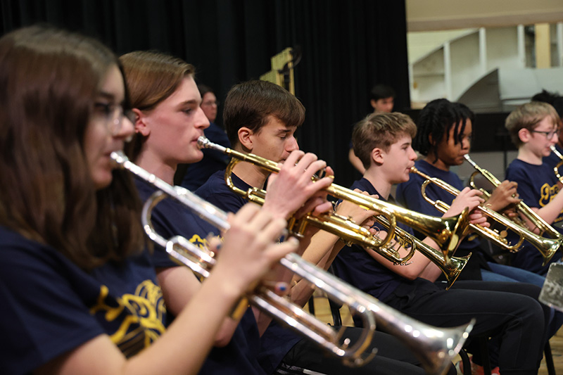 A line of middle schools students playing trumpet.