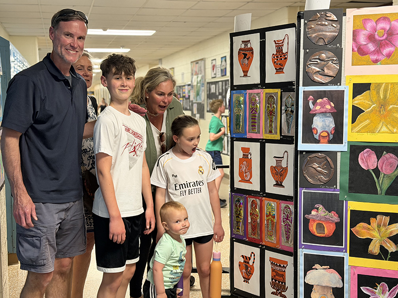 A family of five people look at large displays of artwork.