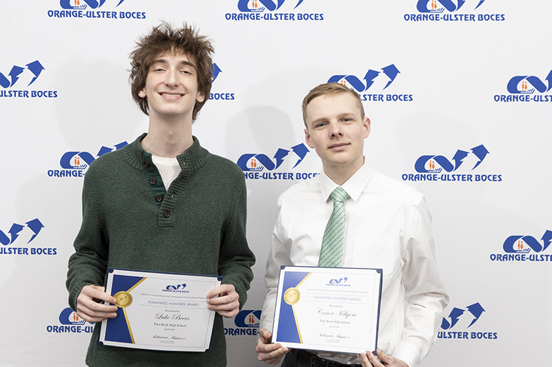 Two high school boys smile and hold certificates.