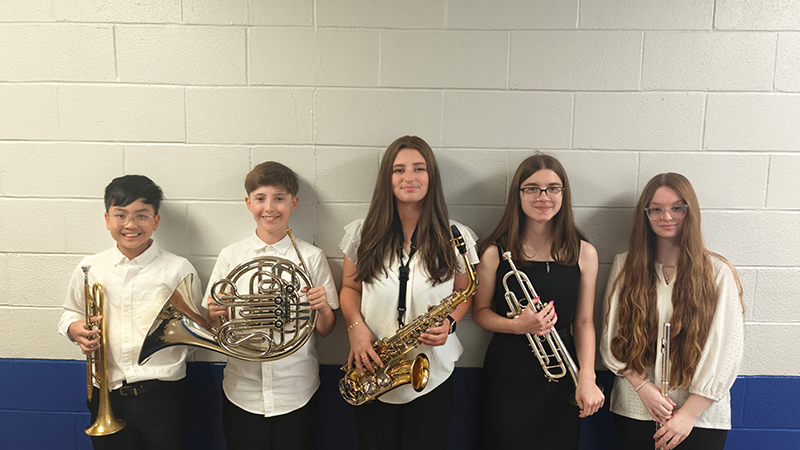 Five middle and high school students stand together holding their instruments.