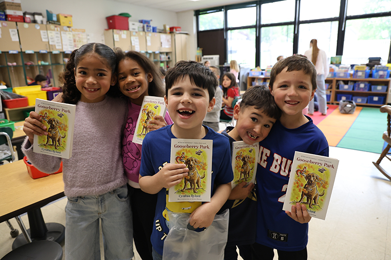 Five elementary students excitedly hold their copies of Gooseberry Park.