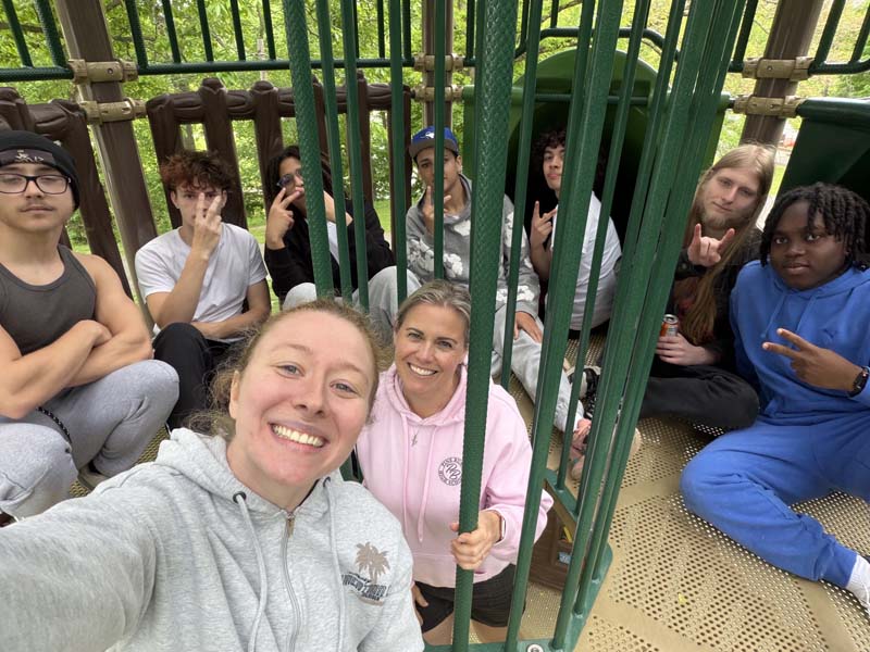 A group of high school kids and a couple adults on a playground.