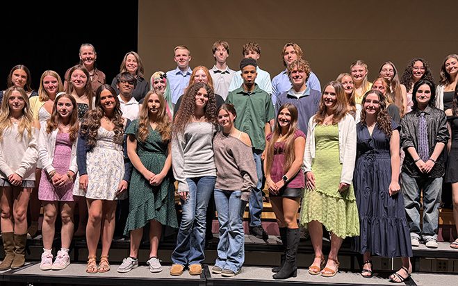 PBHS NAHS w teachers web A group of 26 high school students who are smiling stand on a stage. With them are three women as well.
