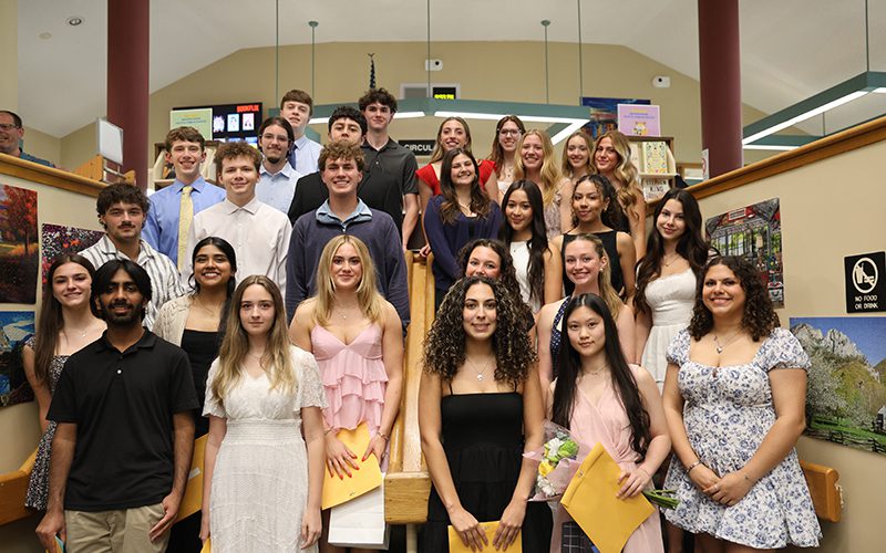 A group of 27 high school students standing on different levels of steps. All are smiling. They are dressed nicely