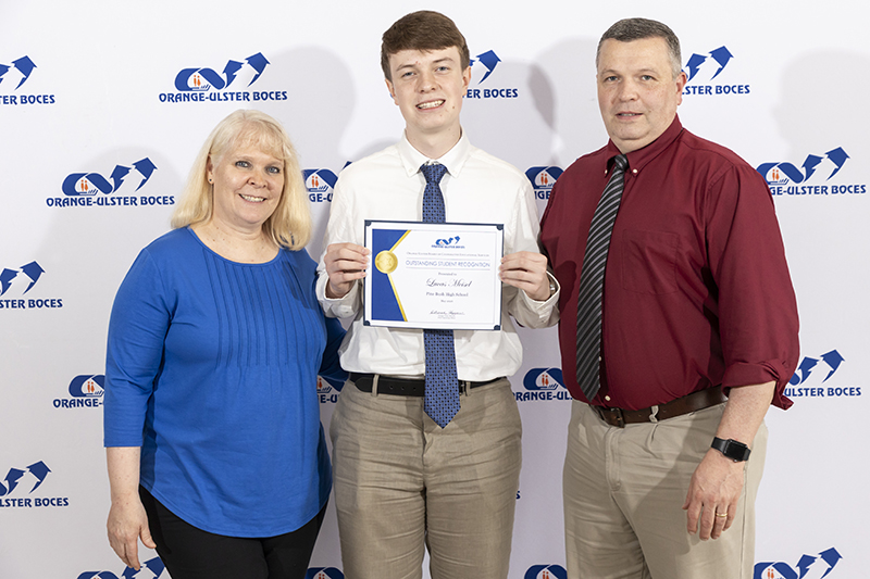 A young man holds a certificate. There is a woman and a man on either side of him.