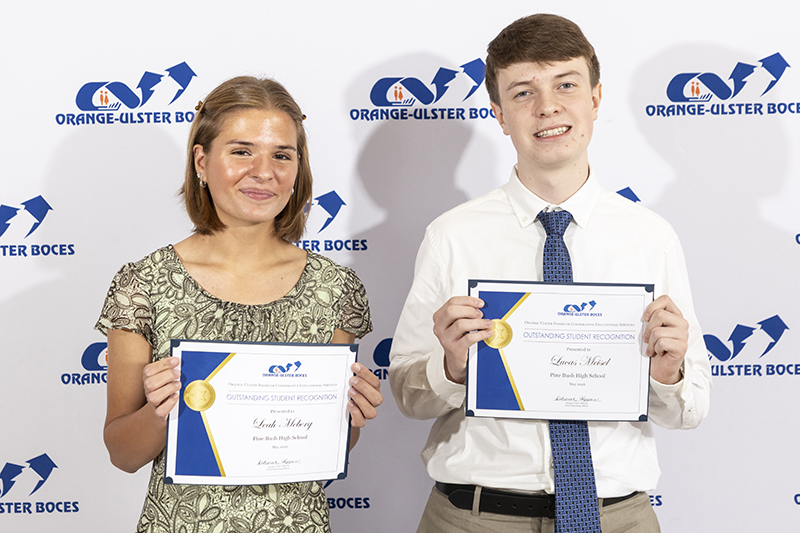 Two high school students dressed nicely hold certificates.