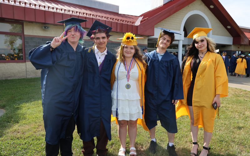A group of high school graduates in blue and gold caps and gowns