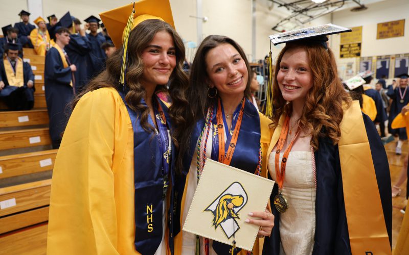Three high school girls in gold and blue caps and gowns.