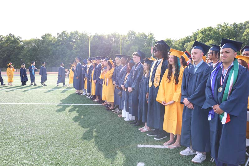 A long line of graduates, in blue and gold caps and gown.