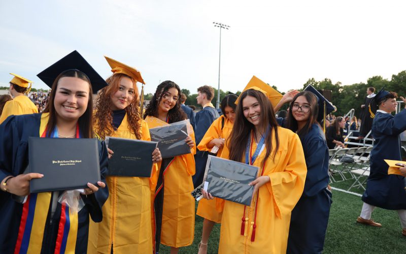 A group of high school graduates in blue and gold caps and gowns