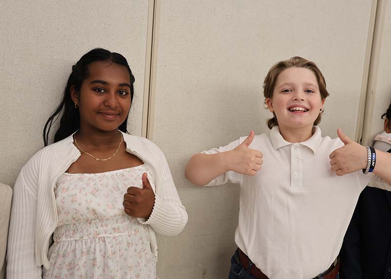 A fifth-grade girl and boy give thumbs up.