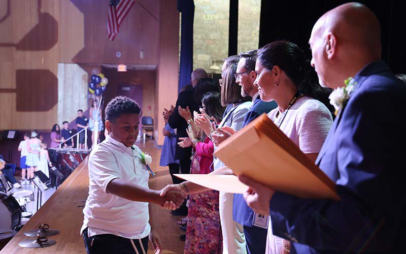 A fifth-grade boy shakes hands with adults.