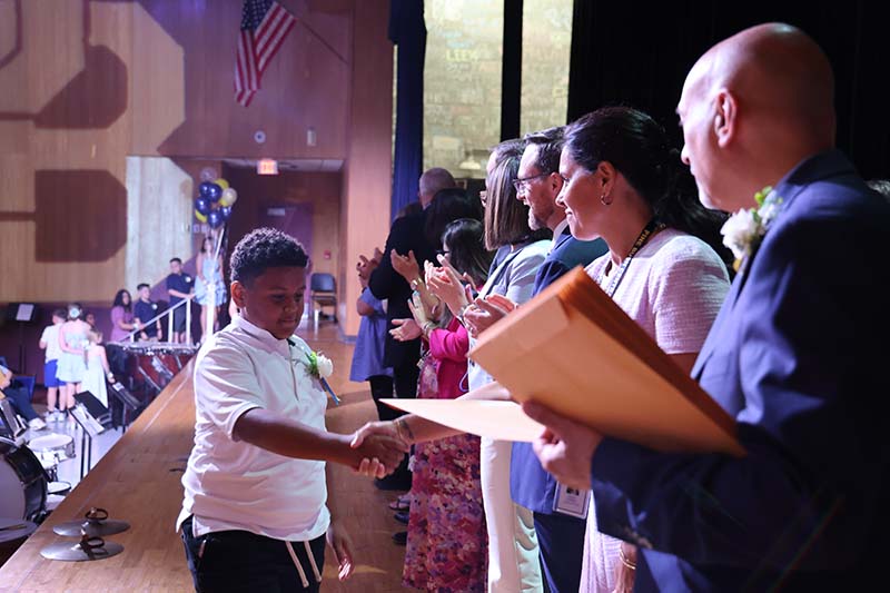 A fifth-grade boy shakes hands with adults.