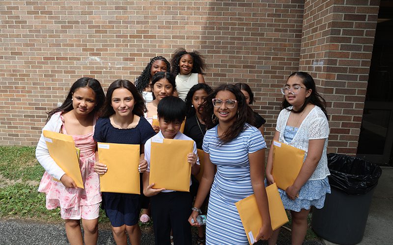 Adults in back and children in front holding dictionaries