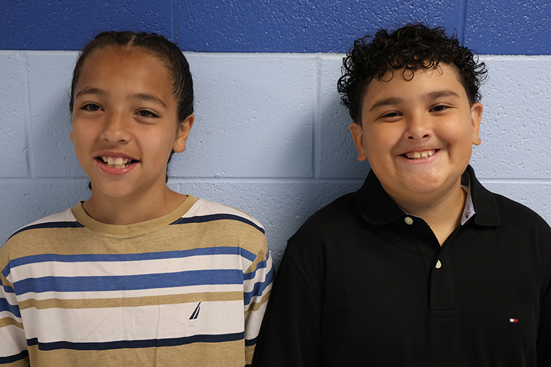 Two fifth-grade boys stand together and smile.