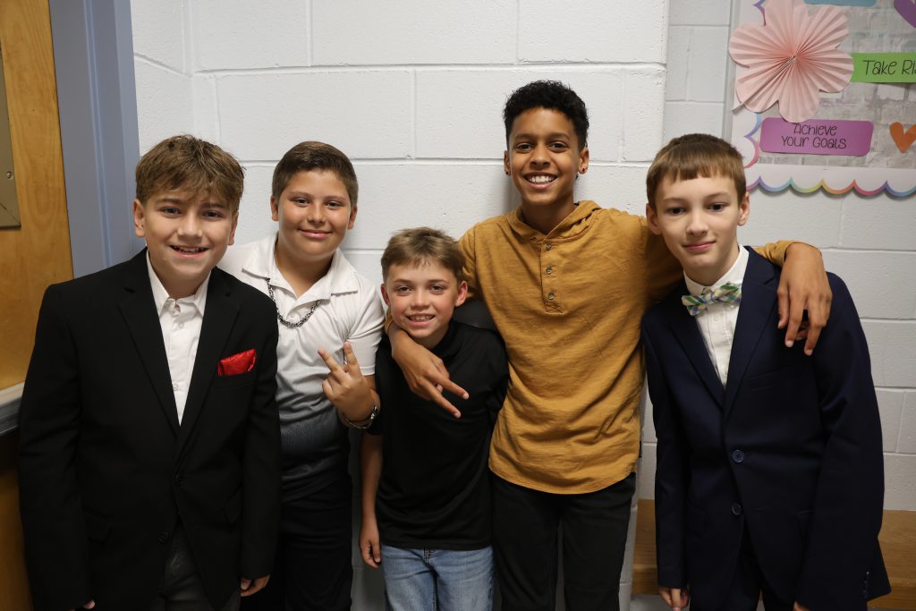 Five fifth-grade boys stand together and smile.