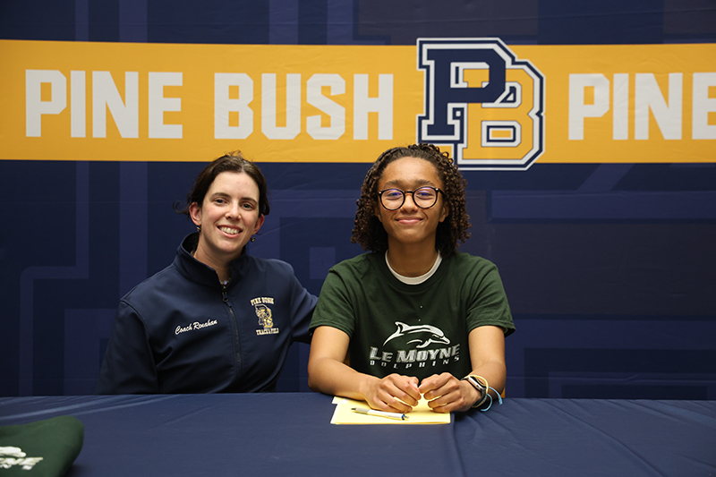 A woman sits next to a high school senior girl who just signed her national letter of intent to run track in college.