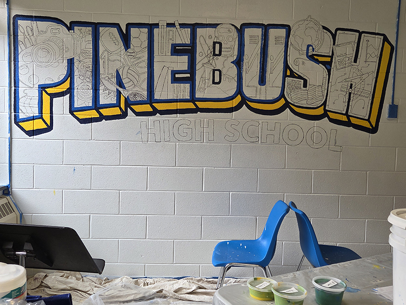 A muralis starting to come together. The letters are outlined and say PineBush in blue and gold.