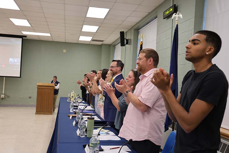 A group of adults stand and applaud.