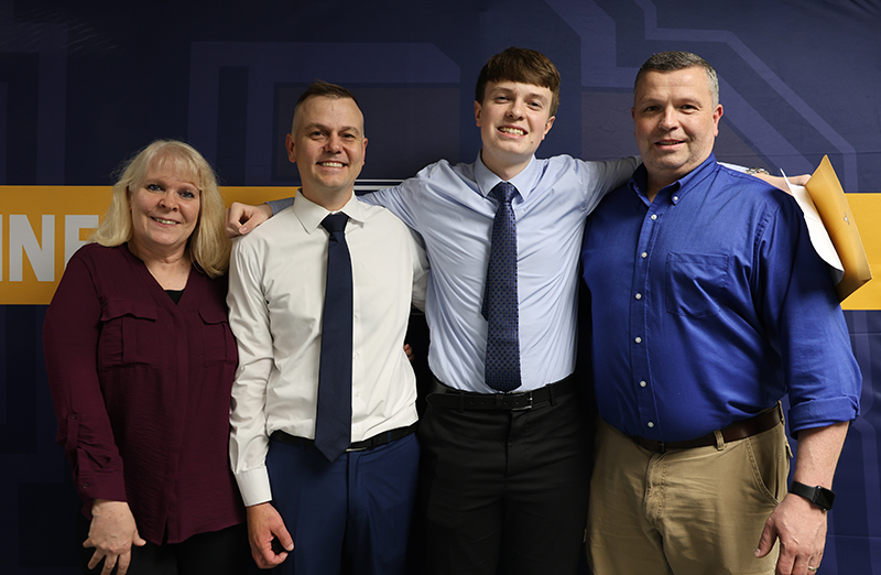 A woman and three men stand together smiling.