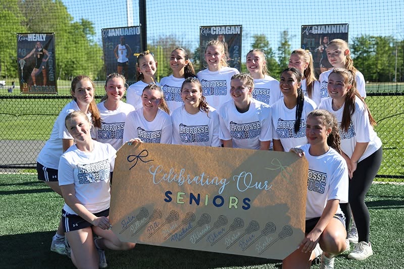 A group of 14 high school girls holding a sign that says we love our seniors.