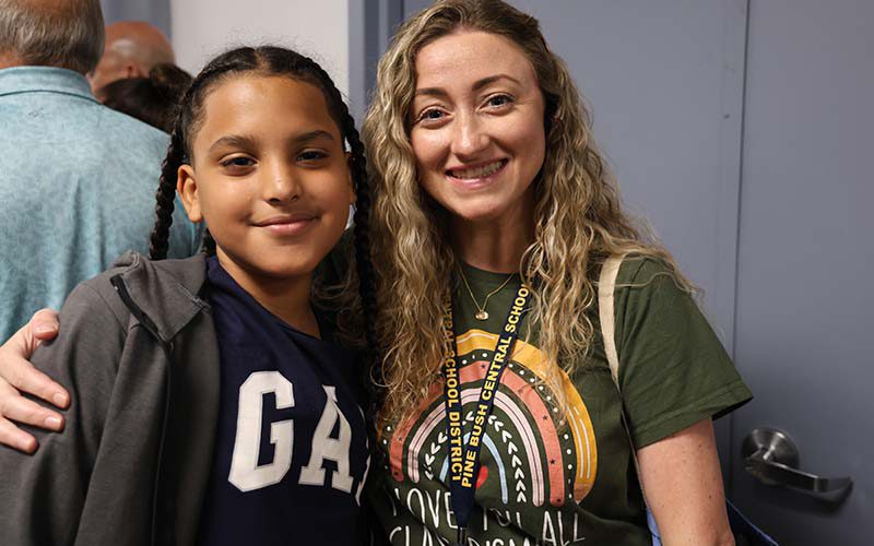 A woman with long blonde hair stands with a fifth=grade boy with long brown braids. They are both smiling.