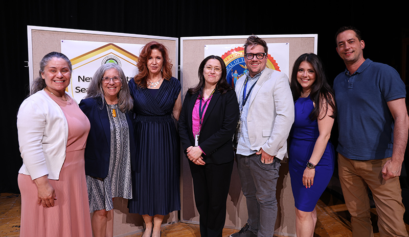 A group of seven people stand together and smile.