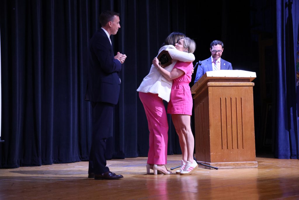 women hugging on stage