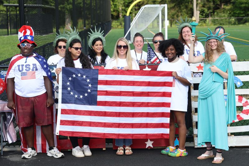 group of students and teachers holding up flag