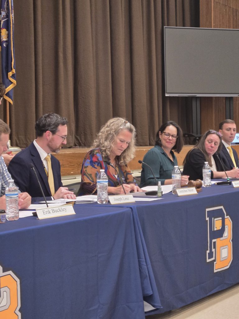 people sitting at a desk while one person signs something