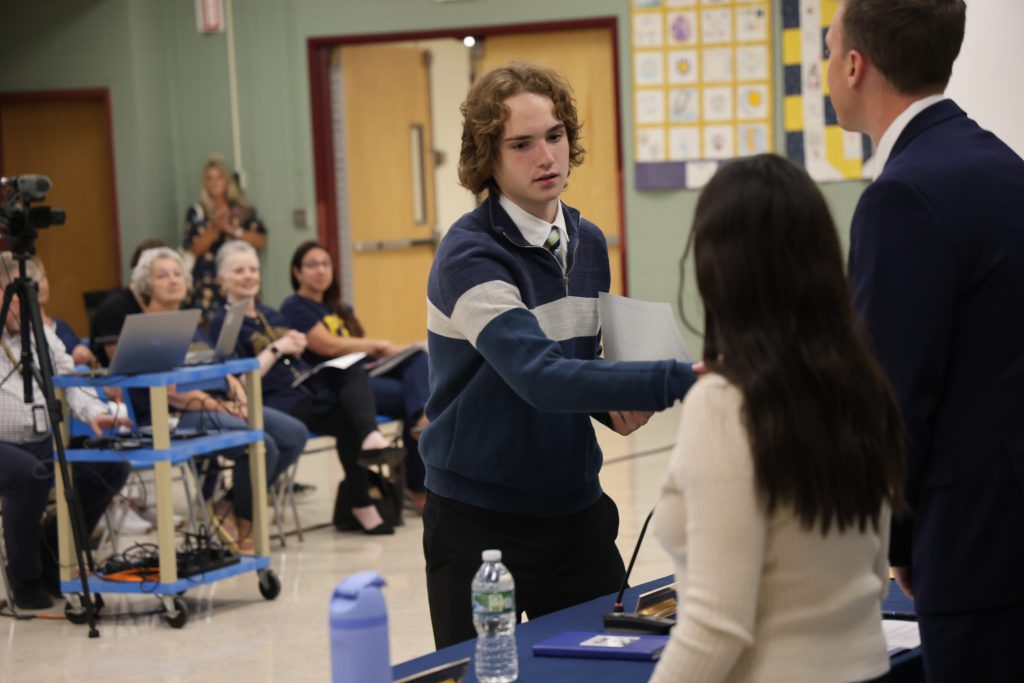 student shaking hands with staff members