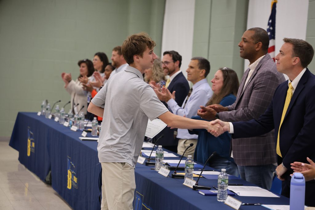 student shaking staff members hand