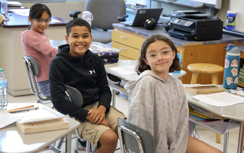 Adults in back and children in front holding dictionaries