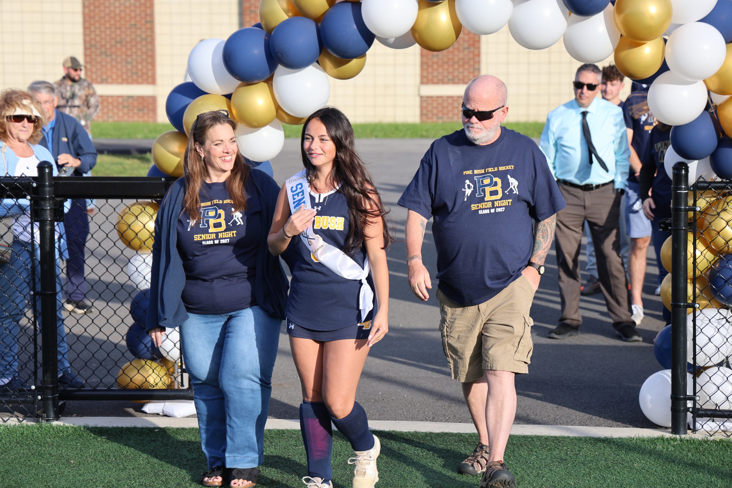 girl walking with her parents on a sports field