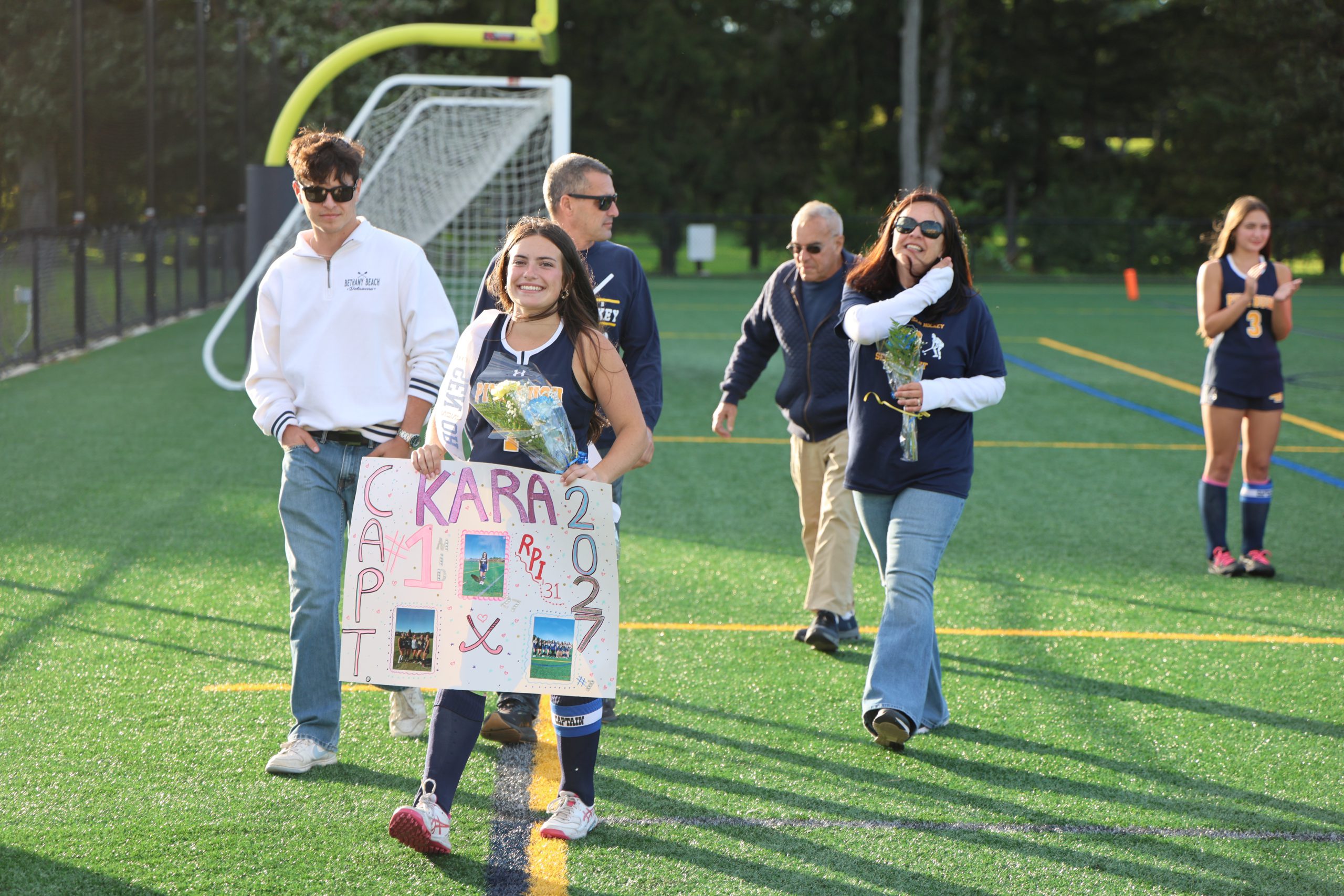 girl walking down a sports field with her family