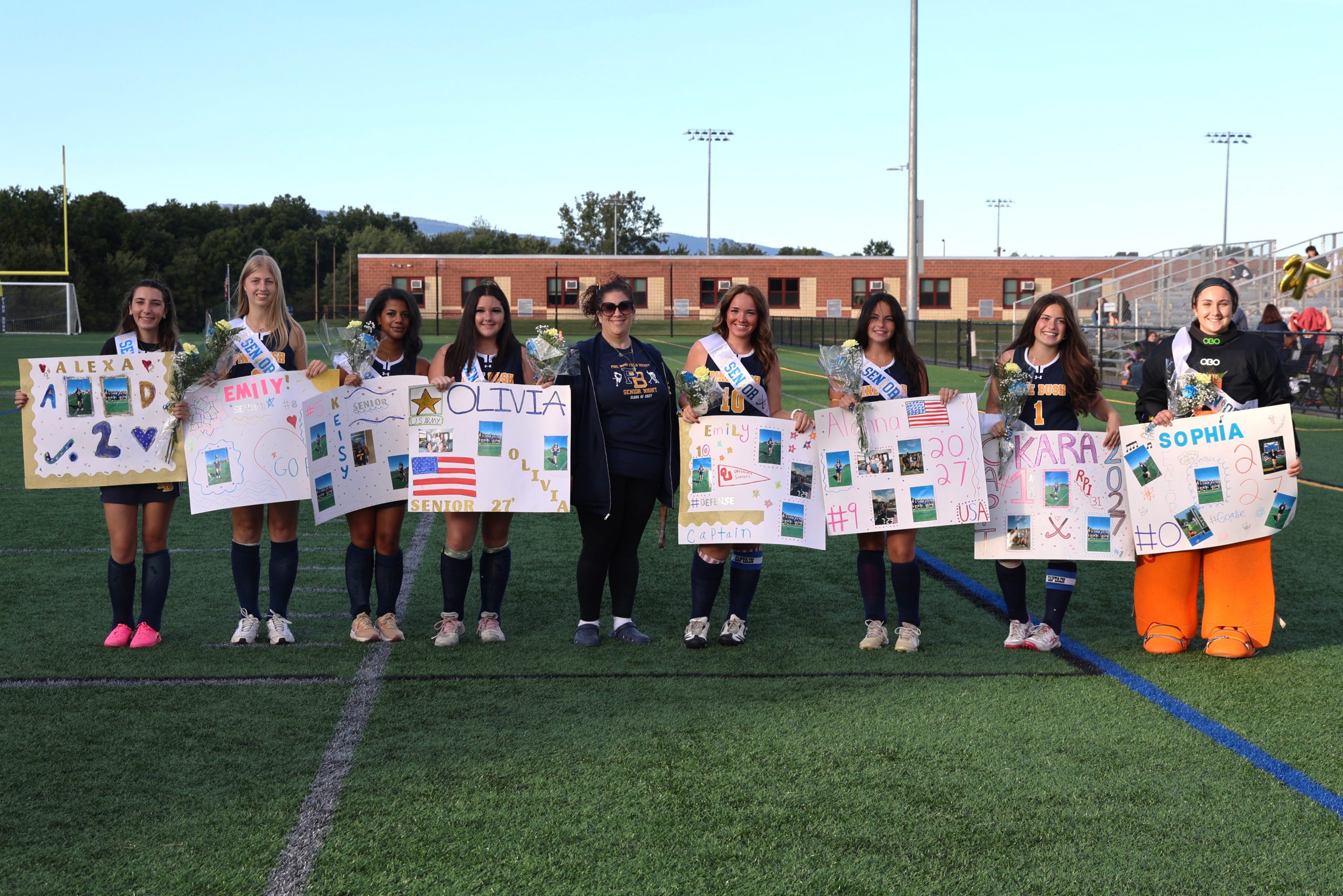 field hockey team and their coach standing together for photo