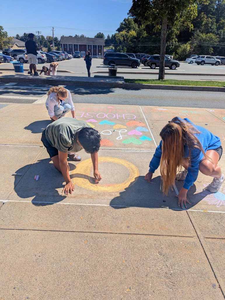 kids writing with chalk on sidewalk