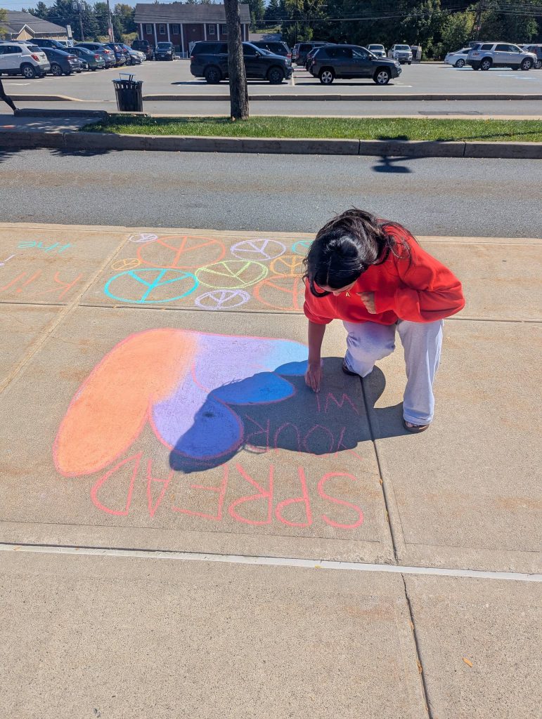 kid writing with chalk on sidewalk