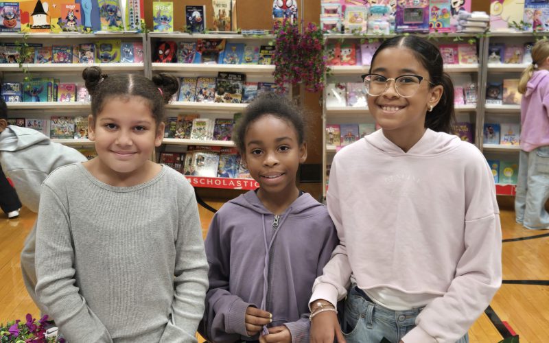 three students standing together at a book fair