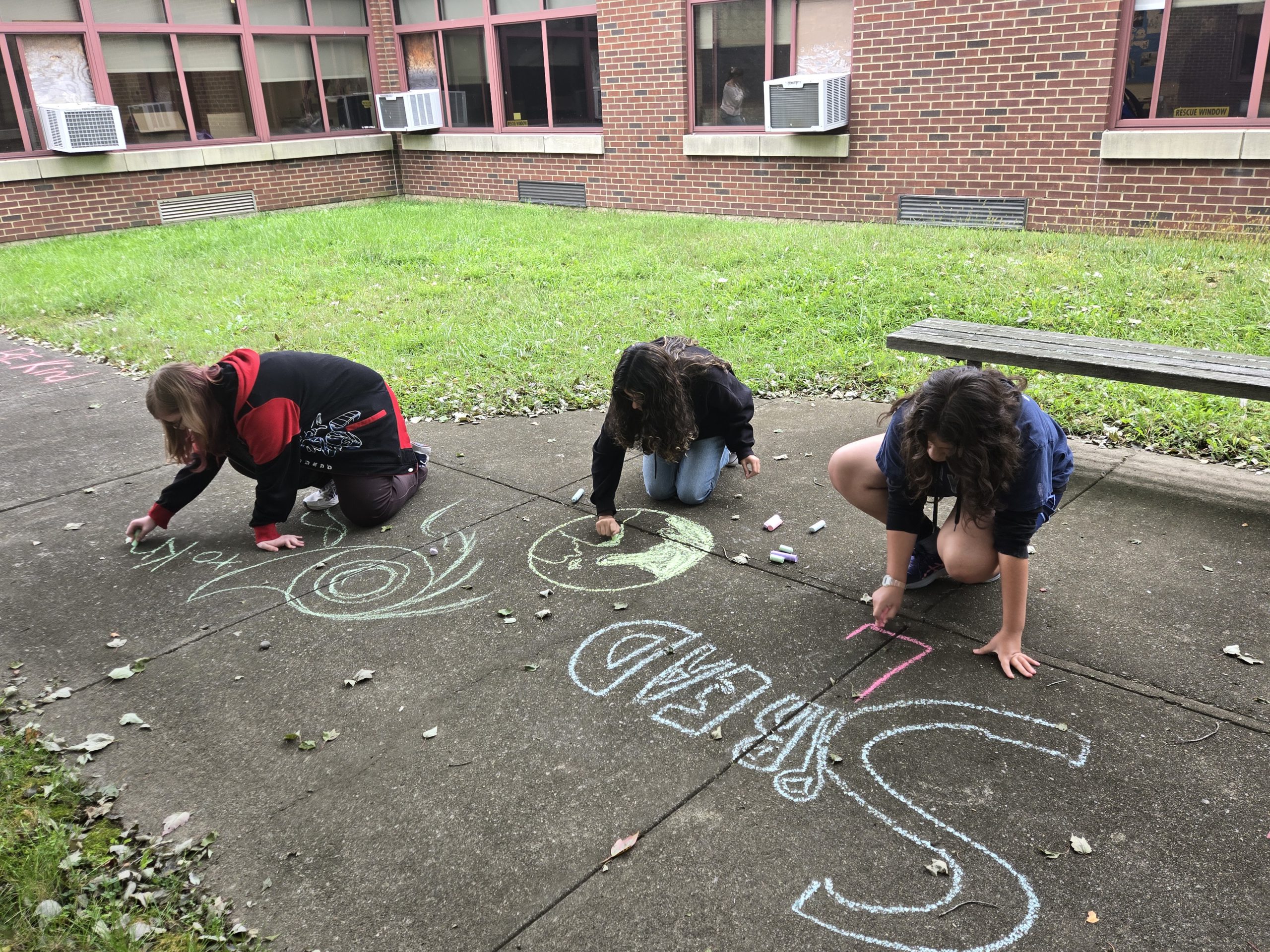 kids writing with chalk on sidewalk