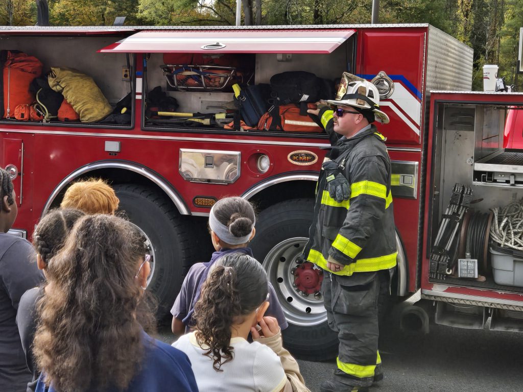 firefighter teaching kids about equipment in the fire truck